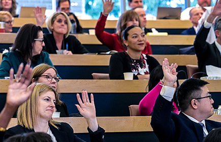 Photo of law students in class with hands raised