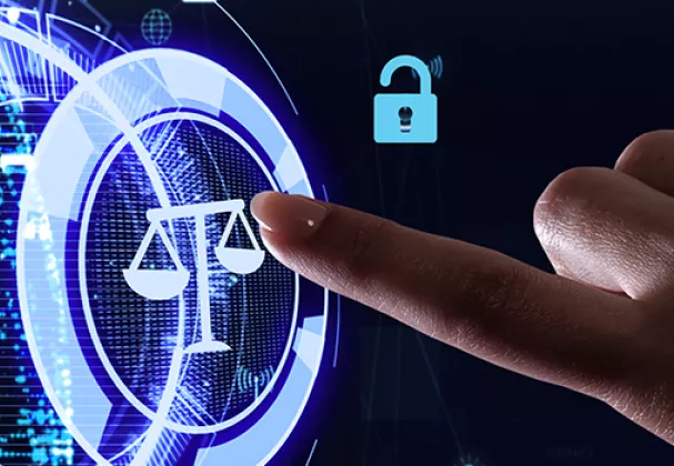 Photo of a finger pointing to a computer screen icon of the scales of justice